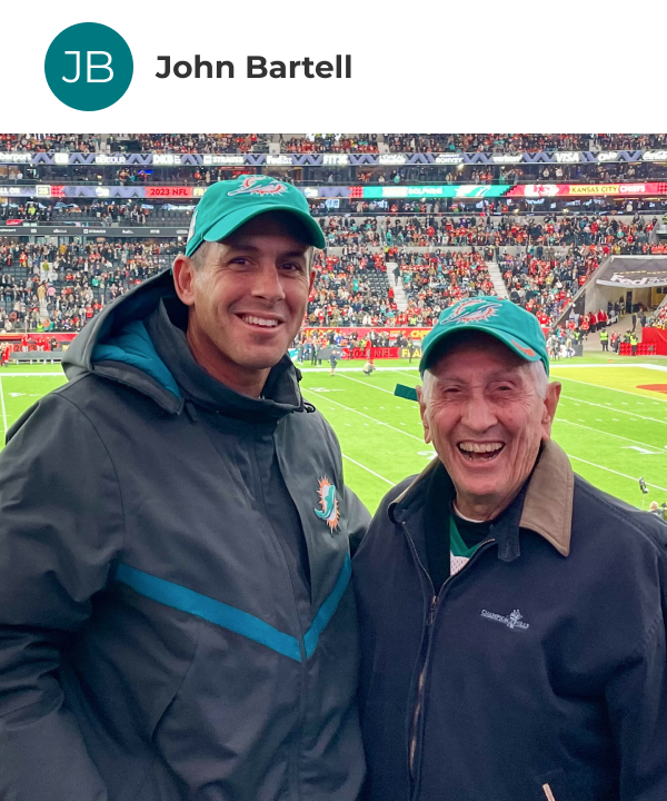 john-bartell John Bartell posing with his son with their backs to the field at Deutsche Bank Park in Germany for the 2023 Dolphins vs. Chiefs international game.